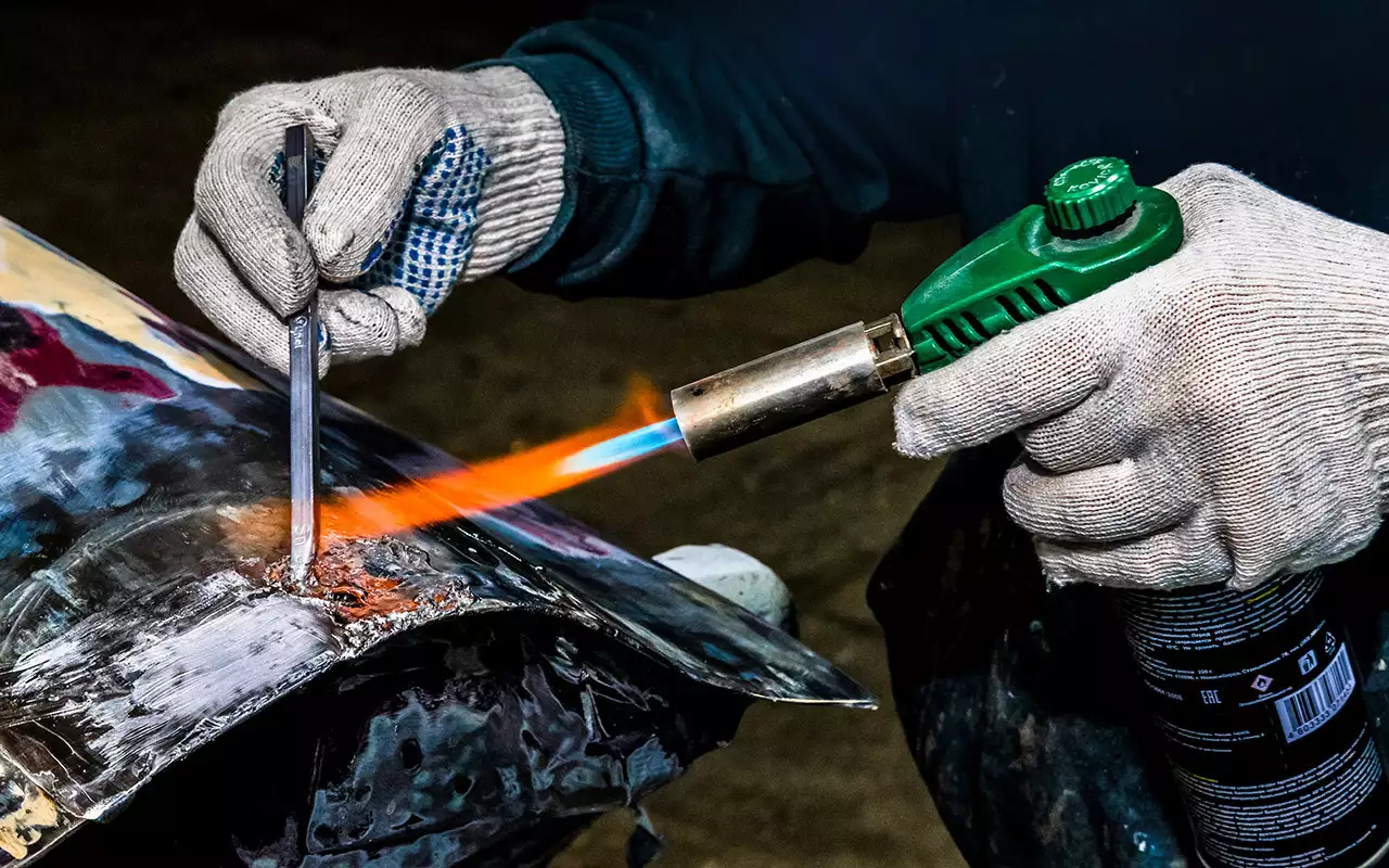 Один из примеров лужения – спасение переднего крыла седана Oldsmobile Aurora. Новая деталь очень дорогá, и ее не так-то просто найти. Крыло правили после серьезной вмятины на стыке с дверью. Металл значительно ослаб от растяжения и коррозии. В этом случае олово предпочтительнее шпаклевки.