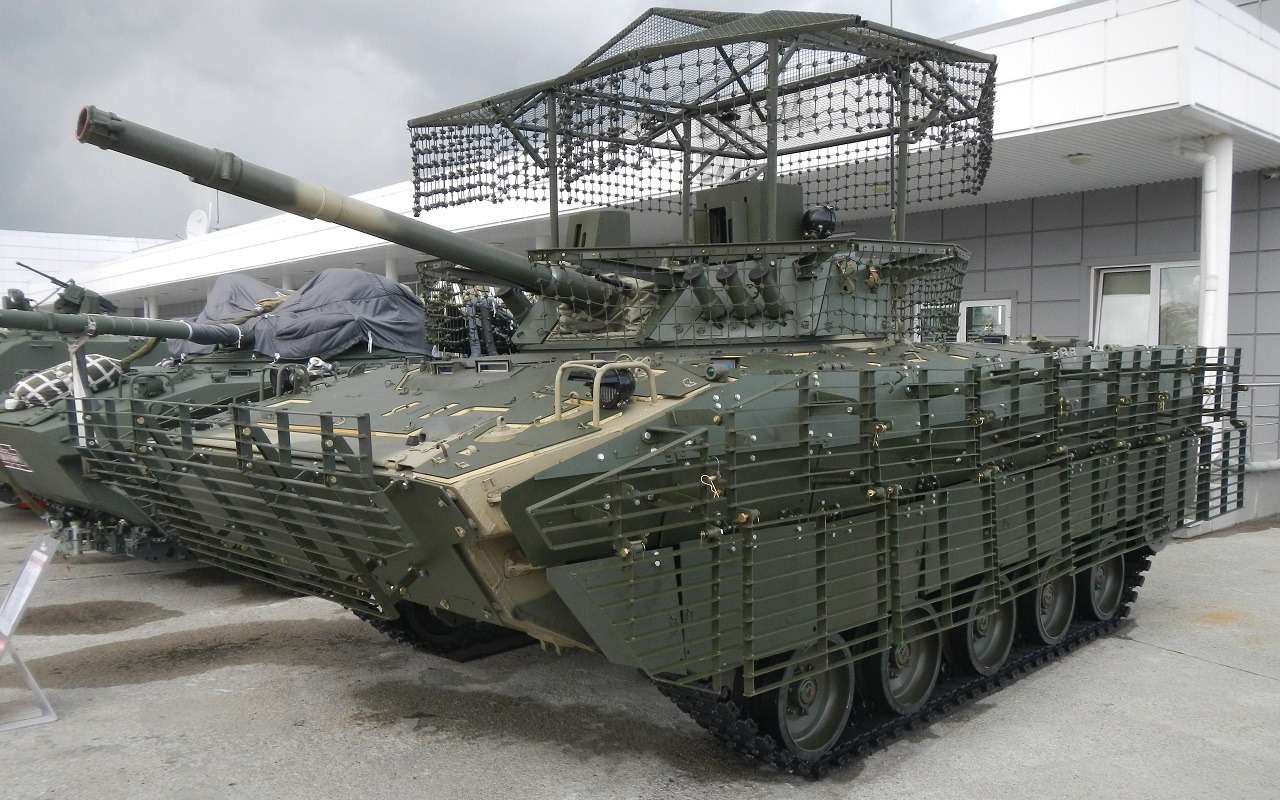 Боевая машина десанта БМД-4М с комплектом дополнительной защиты, сетками от FPV-дронов и боеприпасов квадрокоптеров. Объем усиленного бронирования хорошо виден на фото. Алюминиевый корпус БМД – песчаного цвета, броневые экраны — зеленого.