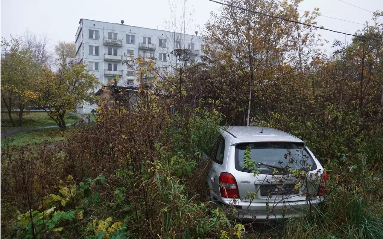 Старый брошенный автомобиль во дворе пятиэтажки.