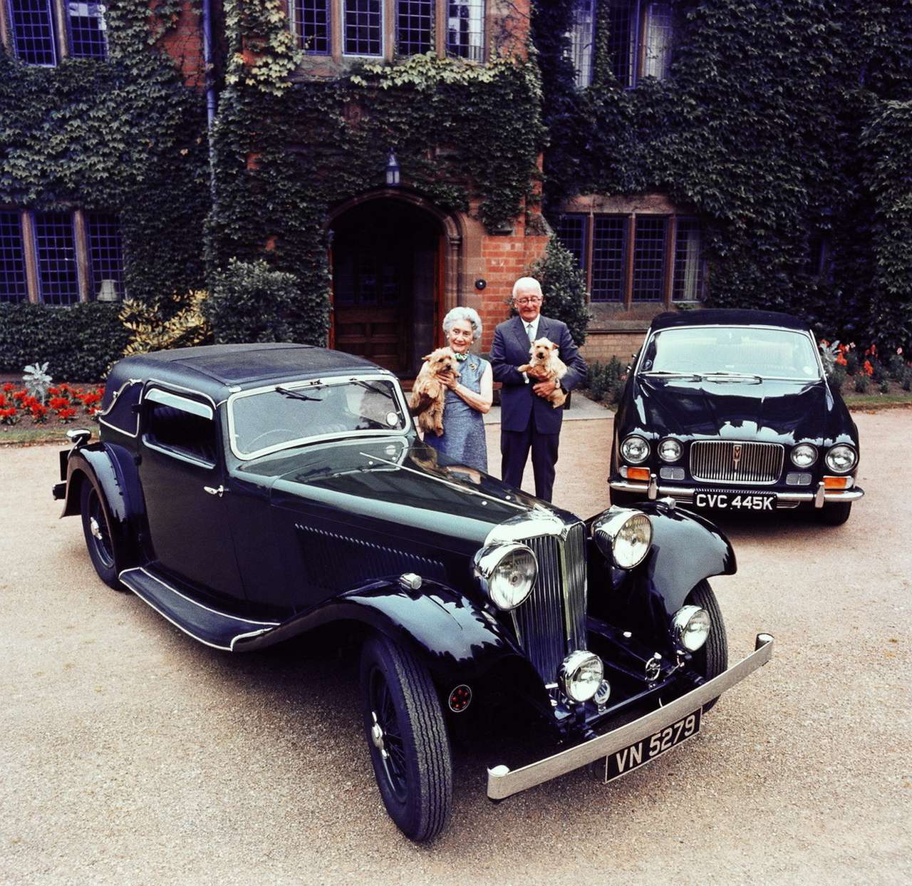 Чета Лайонсов с любимыми терьерами возле первого автомобиля, SS1 (1931-1936 гг.) и модели XJ6 (1968-1973 гг.). У Греты и Уильяма Лайонсов было две дочери, Патрисия, родившаяся в 1927-м, и Мэри, 1937 года рождения. Сын Джон Майкл, появившийся на свет в 1930-м, в 1955-м погиб в автокатастрофе, когда поехал в Ле Ман смотреть, как будут выступать машины отца. (Jaguar D-Type победил в абсолютном зачете.) Супруга переживет Уильяма Лайонса на год